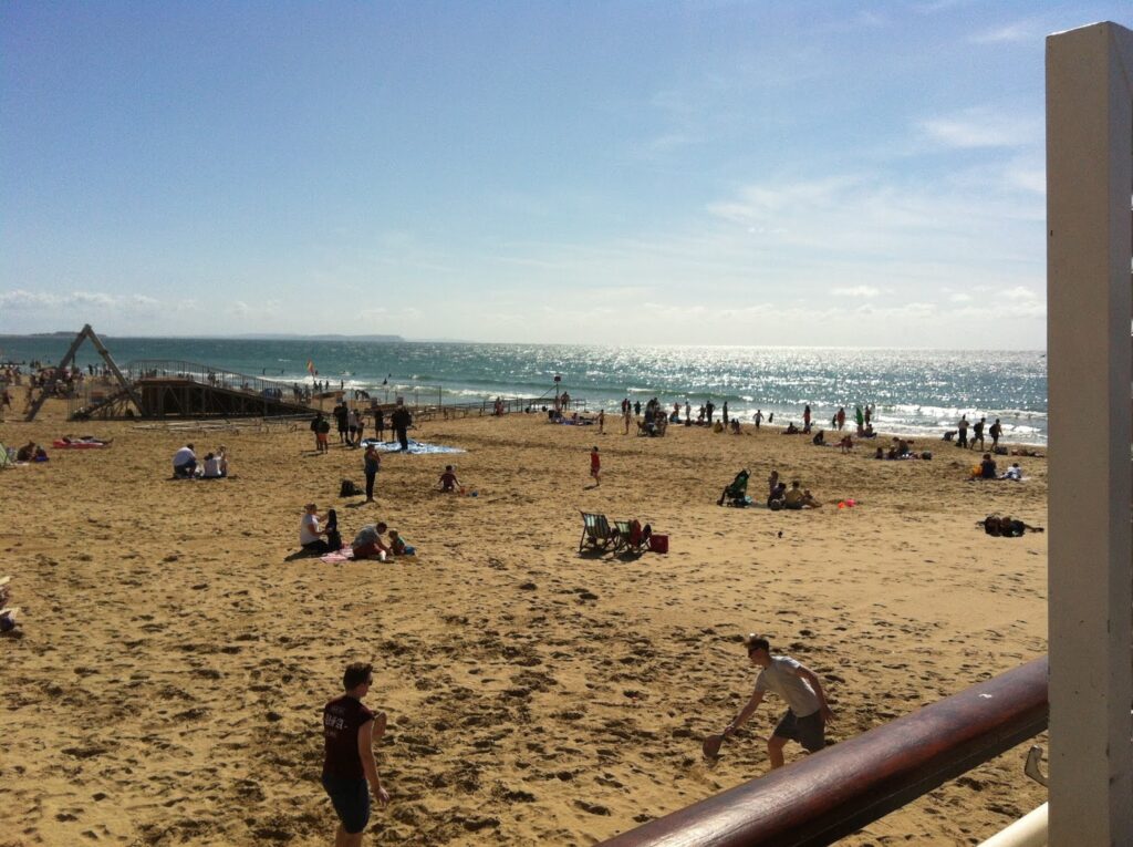 Sand Bournemouth beach with people sunbathing and swimming in the sea