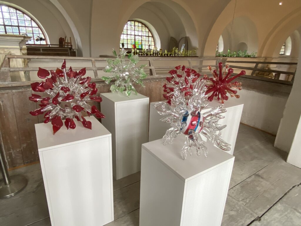Four corona virus sculptures representing Helping hands, Hope and New life, Love and Kisses and smiles on displace at the church in Kunratice u Cvikova