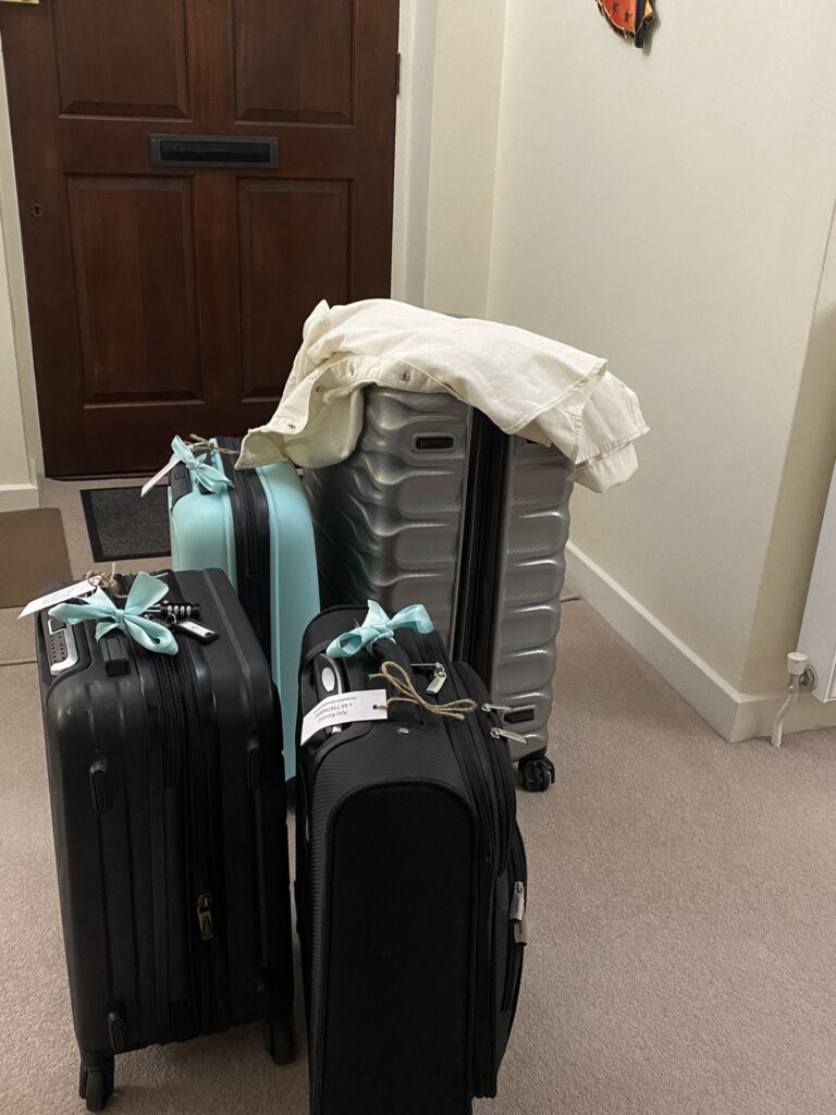 Packed black and silver suitcases in hallway with blue ribbons