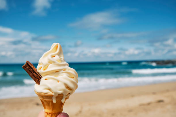 Melting Ice cream cone with flake at Fistral beach, Newquay, Cornwall on a bright sunny June day.
