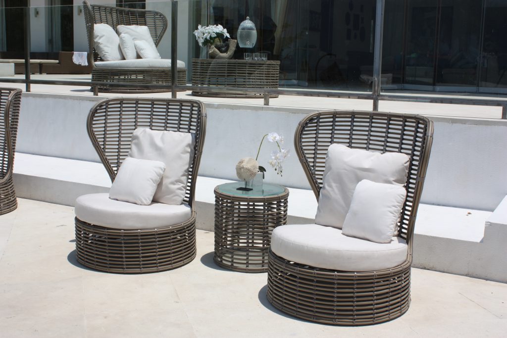 Cane furniture with white cushions and side cane table creating moroccan garden vibes