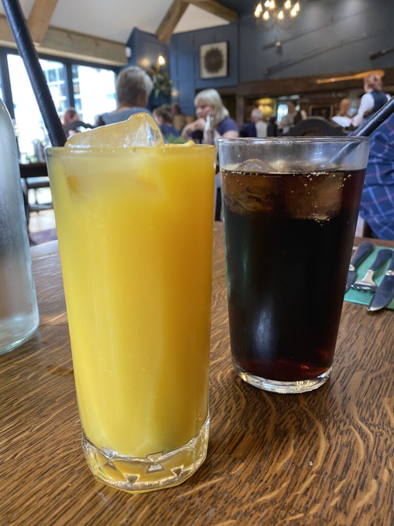 Two glasses with orange juice and coco cola